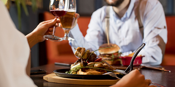 Two people enjoying a pre-show dinner and toasting wine glasses at a restaurant.