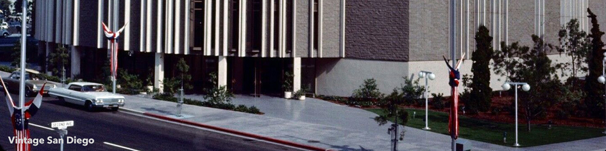 1960s exterior of the San Diego Civic Theatre with its vertical façade panels and a classic white car parked along the street.