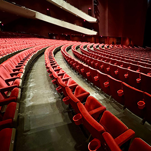 Wide view of the Civic Theatre auditorium showing rows of the curve of empty red seats and loge seating area.